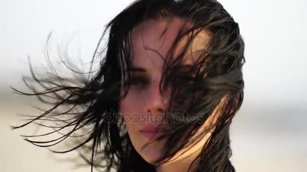 Портрет красивой девушки, улыбающейся на пляже на закате солнца с волнистыми волосами . — стоковое видео