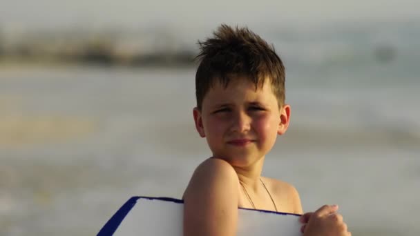Söt grundskola pojke surfer poserar med en styrelse . — Stockvideo