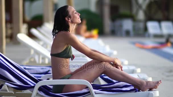 Retrato de una hermosa chica sonriendo en la playa al atardecer con el pelo ondulado . — Vídeo de stock
