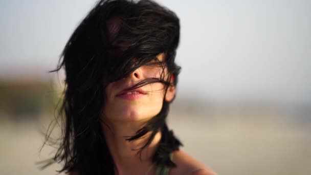 Portret de fată frumoasă zâmbind pe plajă la apus de soare cu păr ondulat . — Videoclip de stoc