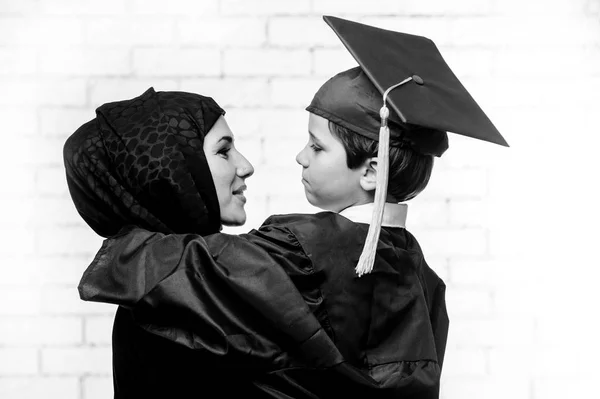 Árabe madre posando con su hijo graduado en el estudio —  Fotos de Stock