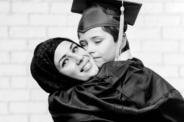 Arabic mother posing with graduated son on white background. — Stock Photo, Image