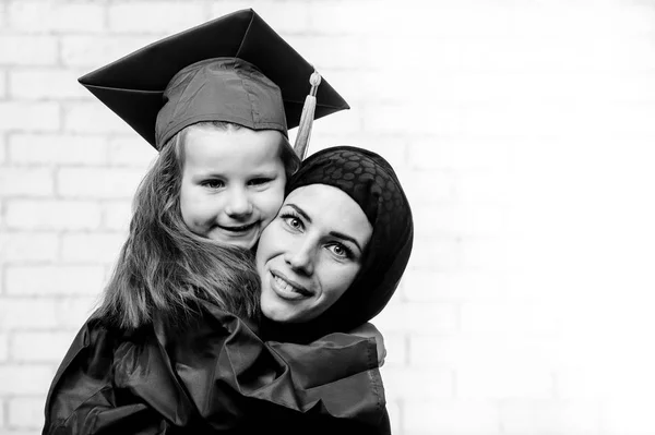 Árabe madre posando con graduación im primaria escolar hija . —  Fotos de Stock