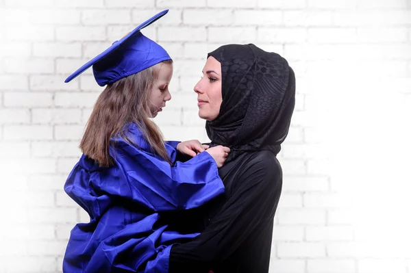 Árabe madre posando con graduación im primaria escolar hija . —  Fotos de Stock