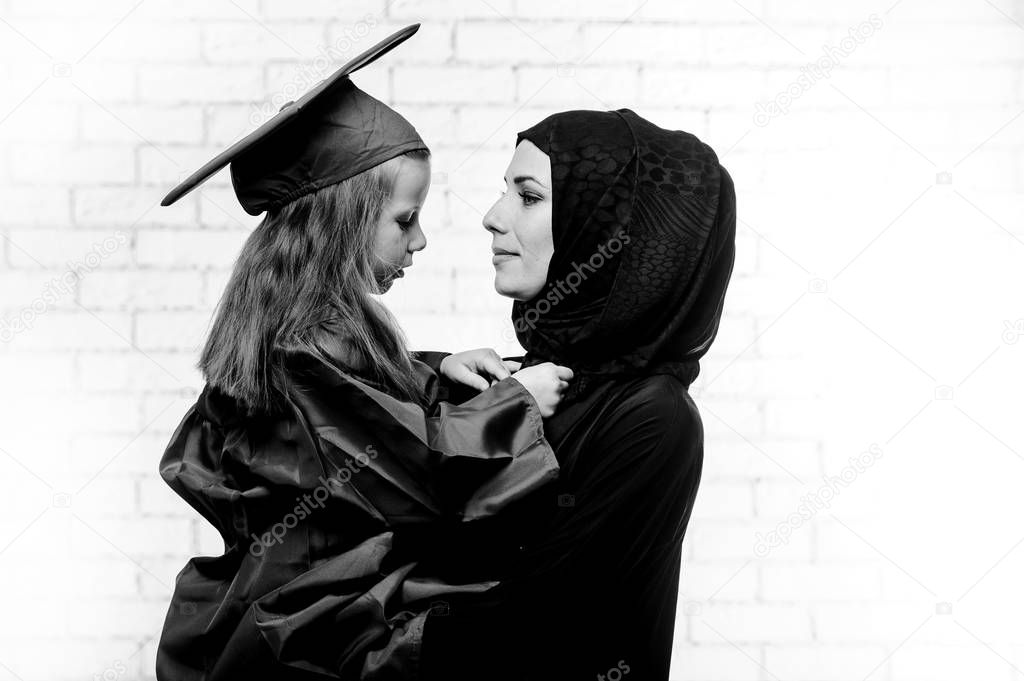 Arabic mother posing with graduated daughter.