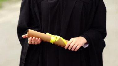 Diploma taşıyan akademik elbiseli genç bir kadın..