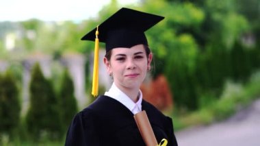 Bardak ve cübbe giymiş güzel bir kız öğrencinin açık hava sahnesi..