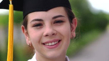 Bardak ve cübbe giymiş güzel bir kız öğrencinin açık hava sahnesi..