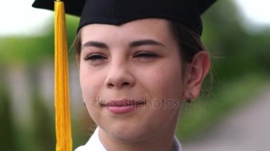 Bardak ve cübbe giymiş güzel bir kız öğrencinin açık hava sahnesi..