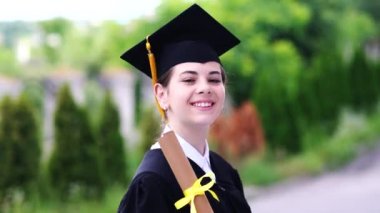 Bardak ve cübbe giymiş güzel bir kız öğrencinin açık hava sahnesi..