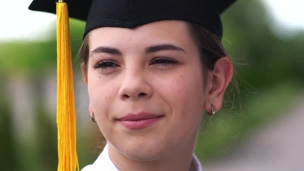 Scène extérieure de belle étudiante diplômée vêtue d'une tasse et d'une robe . — Video