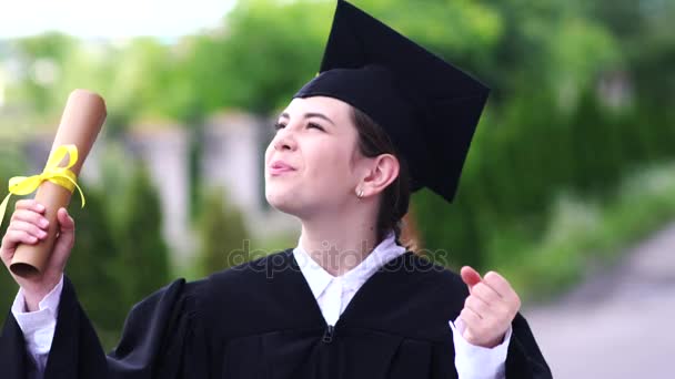 아름다운 여대생 이 컵 과 가운을 입고 졸업하는 모습. — 비디오