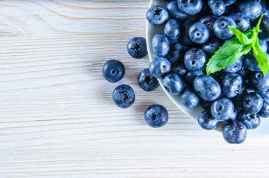 Beyaz ahşap arka planda taze sağlıklı organik yaban mersini