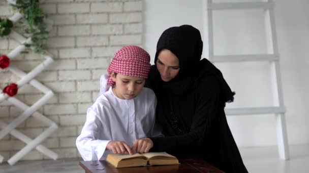 Arabische moeder en zoon lezen binnen. — Stockvideo