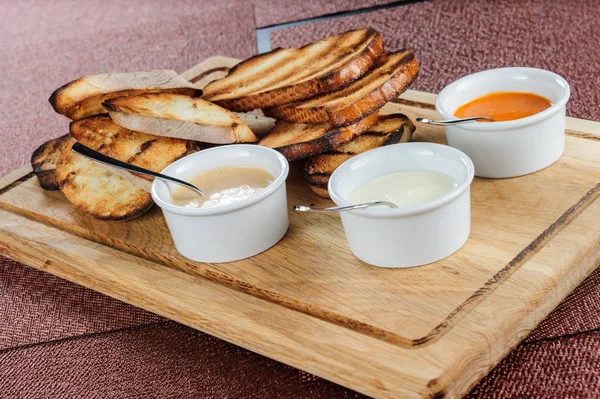 Rebanada de pan tostado empanado con queso y sésamo deslizado en una salsa sobre una tabla de madera —  Fotos de Stock