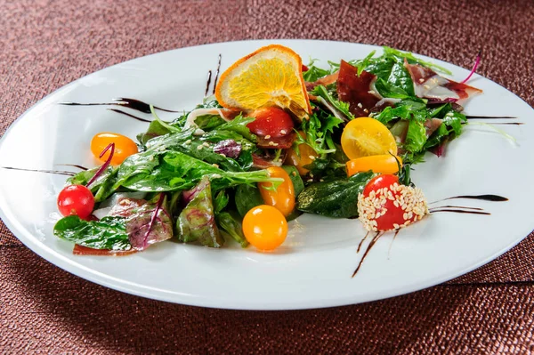 Groene salade, gegarneerd met gele tomaten. — Stockfoto