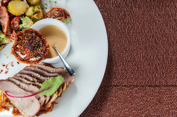 Skivad bakad fläsksida med ångad broccoli, morot, brysselkål och zucchini. — Stockfoto