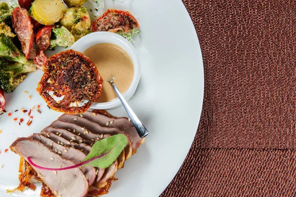 Gebakken varkensvlees met gestoomde broccoli, wortel, spruiten en courgette plakjes. — Stockfoto