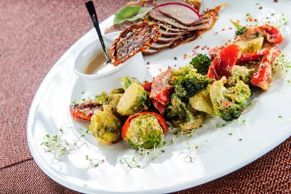 Skivad bakad fläsksida med ångad broccoli, morot, brysselkål och zucchini. — Stockfoto