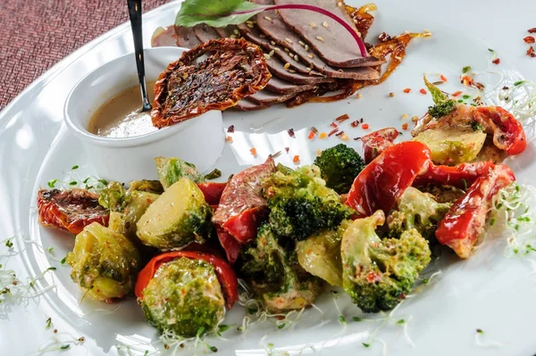 Gebakken varkensvlees met gestoomde broccoli, wortel, spruiten en courgette plakjes. — Stockfoto