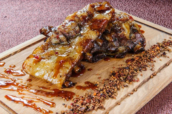 Bife de carne de porco grelhado em placa de corte de madeira sobre mesa de madeira . — Fotografia de Stock