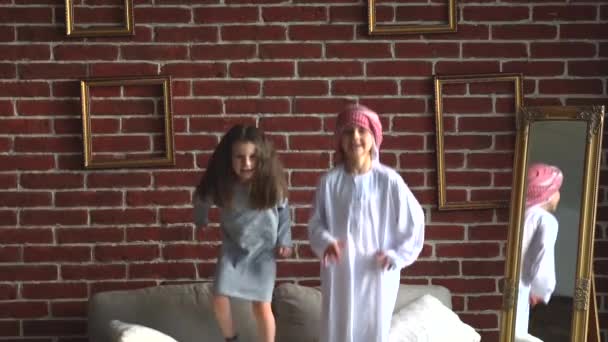 Zwei arabische Kinder springen auf Sofa drinnen. — Stockvideo