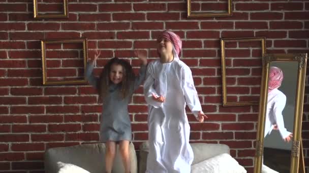 Due bambini arabi saltano sul divano al coperto . — Video Stock