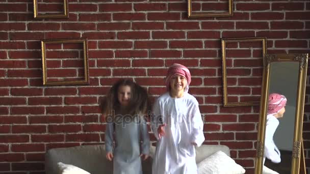 Duas crianças árabes saltar no sofá interior . — Vídeo de Stock