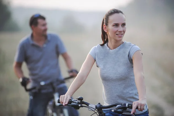 Happy young couple with bicycles in countryside. — Stock Photo, Image