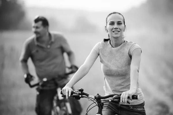 Young couple on bicycles in the field.Black and white. — Stock Photo, Image