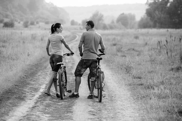 Casal jovem em bicicletas no campo.Preto e branco . — Fotografia de Stock
