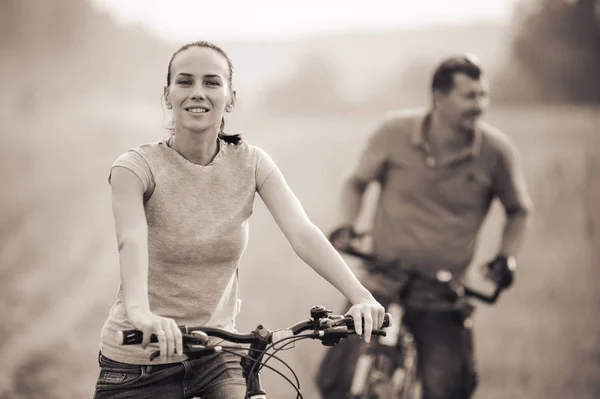 Young couple on bicycles in the field.Black and white. — Stock Photo, Image