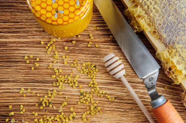 Fresh honey in the comb and the tools of the beekeeper on a brawn vooden background. Flat lay and top view