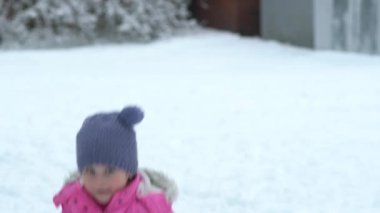 Kış elbiseleri düşen kar topu ile küçük yürümeye başlayan çocuk kız portresi.