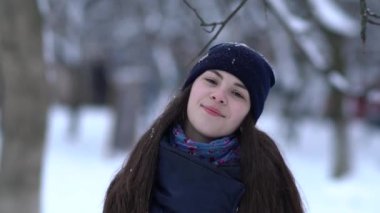 Örgü pembe scurf, eldiven ve şapka kar tanesi üzerinde kar yağışı sırasında mavi arka plan ile güzel bir kadında kış portresi