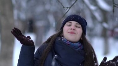 Örgü pembe scurf, eldiven ve şapka kar tanesi üzerinde kar yağışı sırasında mavi arka plan ile güzel bir kadında kış portresi