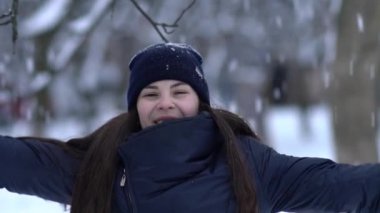 Örgü pembe scurf, eldiven ve şapka kar tanesi üzerinde kar yağışı sırasında mavi arka plan ile güzel bir kadında kış portresi