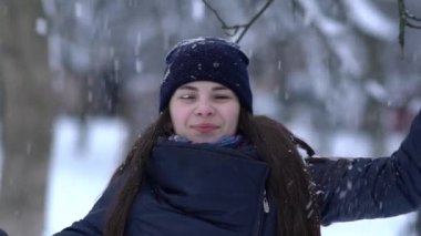 Örgü pembe scurf, eldiven ve şapka kar tanesi üzerinde kar yağışı sırasında mavi arka plan ile güzel bir kadında kış portresi