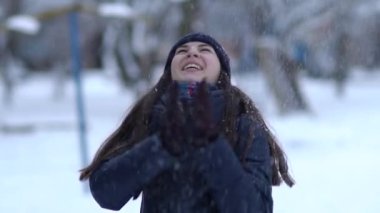 Örgü pembe scurf, eldiven ve şapka kar tanesi üzerinde kar yağışı sırasında mavi arka plan ile güzel bir kadında kış portresi