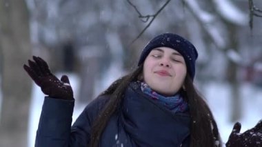 Örgü pembe scurf, eldiven ve şapka kar tanesi üzerinde kar yağışı sırasında mavi arka plan ile güzel bir kadında kış portresi