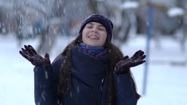 冬天画像的一个美丽的女人在针织粉红色的屑 手套和帽子与雪片在蓝色背景下的降雪 — 图库视频影像
