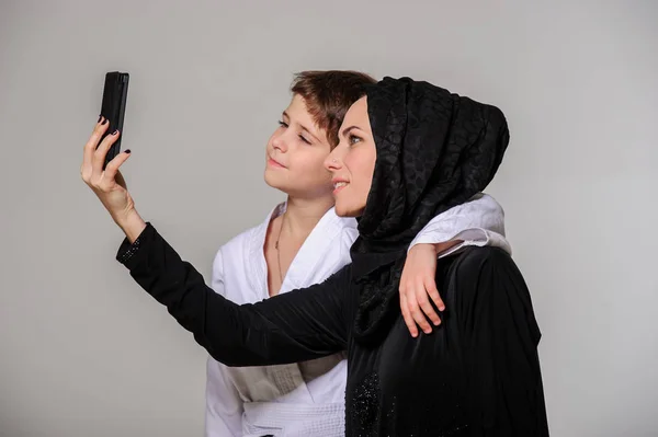 Selfie をしている着物で少し息子と幸せのイスラム教徒ママ — ストック写真