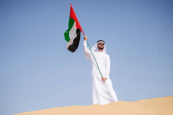 Orgulloso hombre árabe emiratí sosteniendo una bandera de los EAU en el desierto . —  Fotos de Stock
