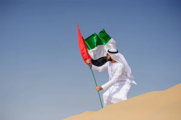 Orgulloso hombre árabe emiratí sosteniendo una bandera de los EAU en el desierto . — Foto de Stock