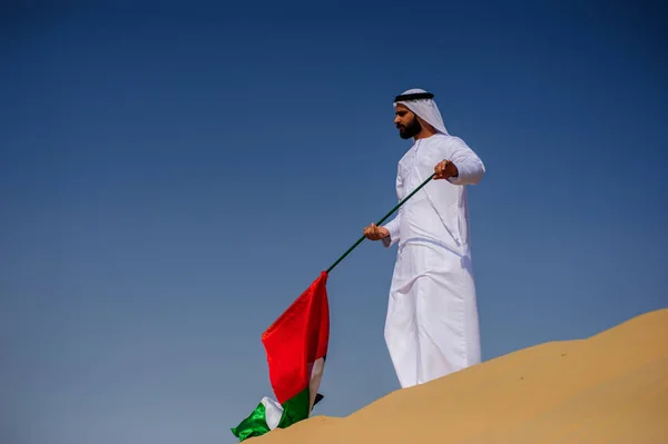 Orgulloso hombre árabe emiratí sosteniendo una bandera de los EAU en el desierto . — Foto de Stock