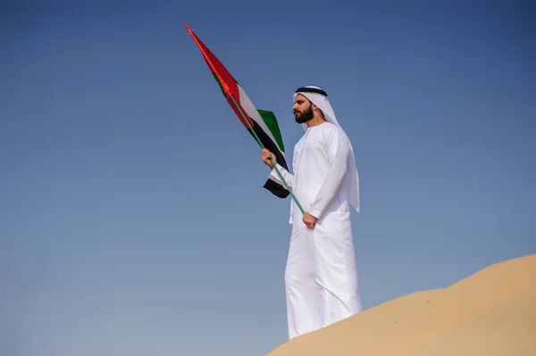 Fier homme émirati arabe tenant un drapeau des EAU dans le désert . — Photo