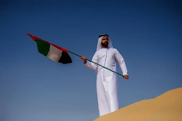 Stolt arabian Emirati man innehar en Uae flagga i öknen. — Stockfoto