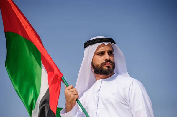 誇りに思ってアラビア首長人砂漠のアラブ首長国連邦の旗を保持しています。. — ストック写真