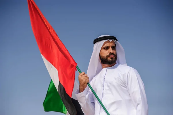 Fier homme émirati arabe tenant un drapeau des EAU dans le désert . — Photo