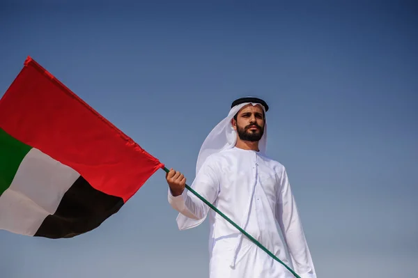 Orgulloso hombre árabe emiratí sosteniendo una bandera de los EAU en el desierto . — Foto de Stock